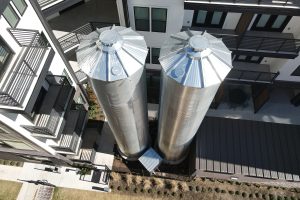 Top-down shot of two tall CorGal Rainwater Harvesting Tanks in an apartment courtyard
